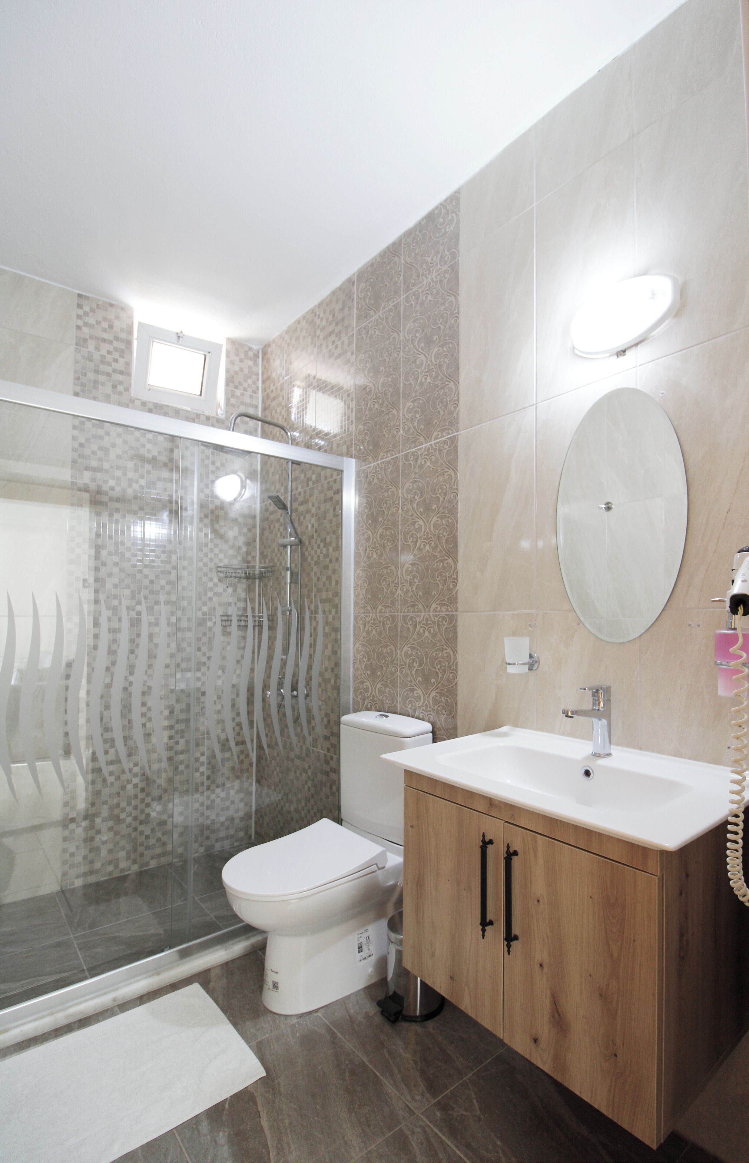 A modern bathroom with a glass-enclosed shower, a white toilet, and a wooden vanity with a mirror.