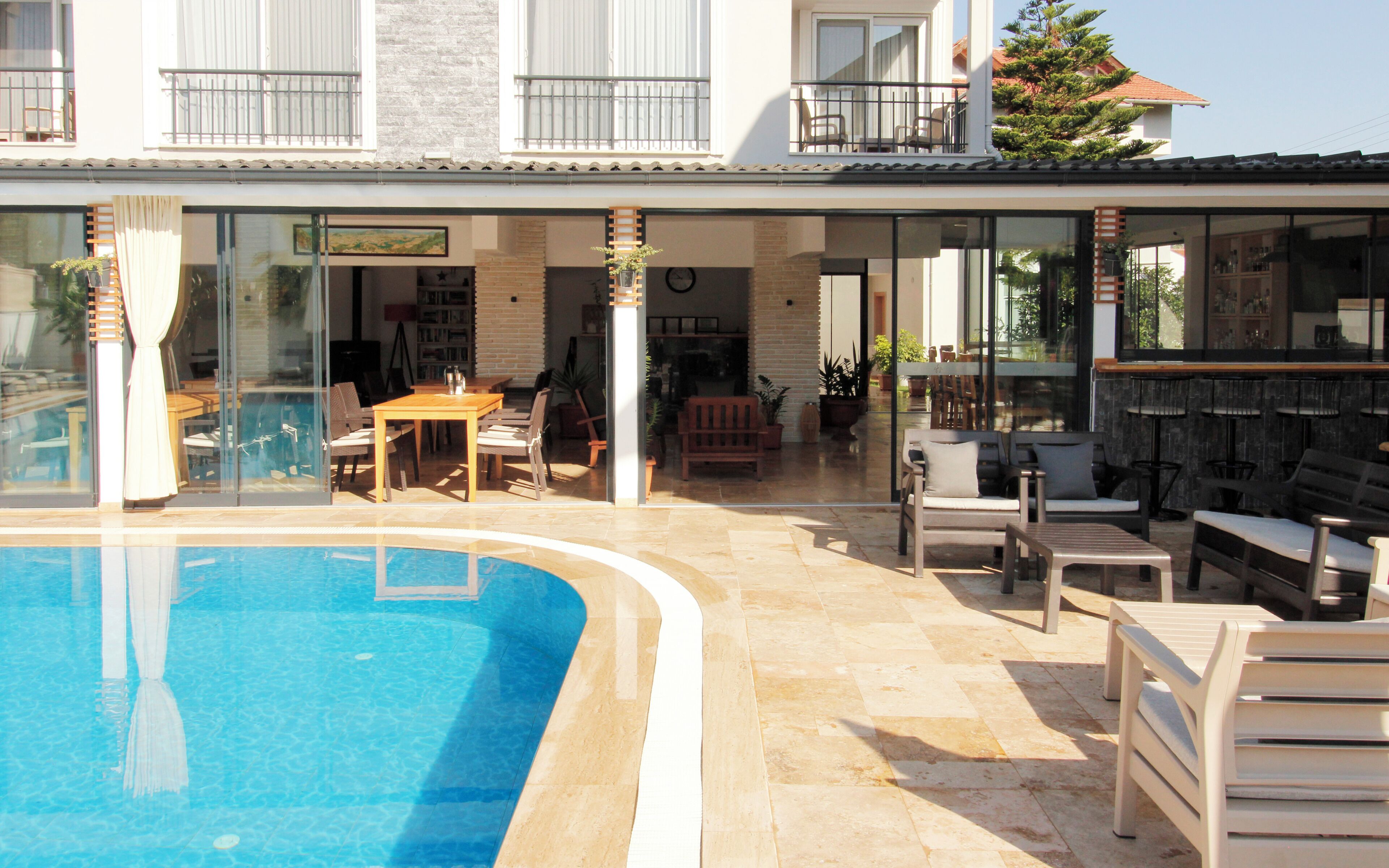 A poolside area with a pool, outdoor seating, and a view of the building's interior.