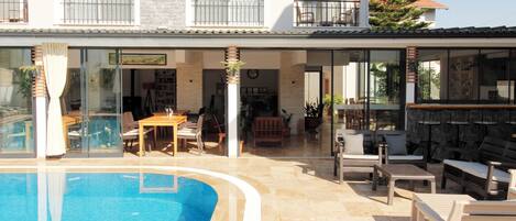 A poolside area with a pool, outdoor seating, and a view of the building's interior.