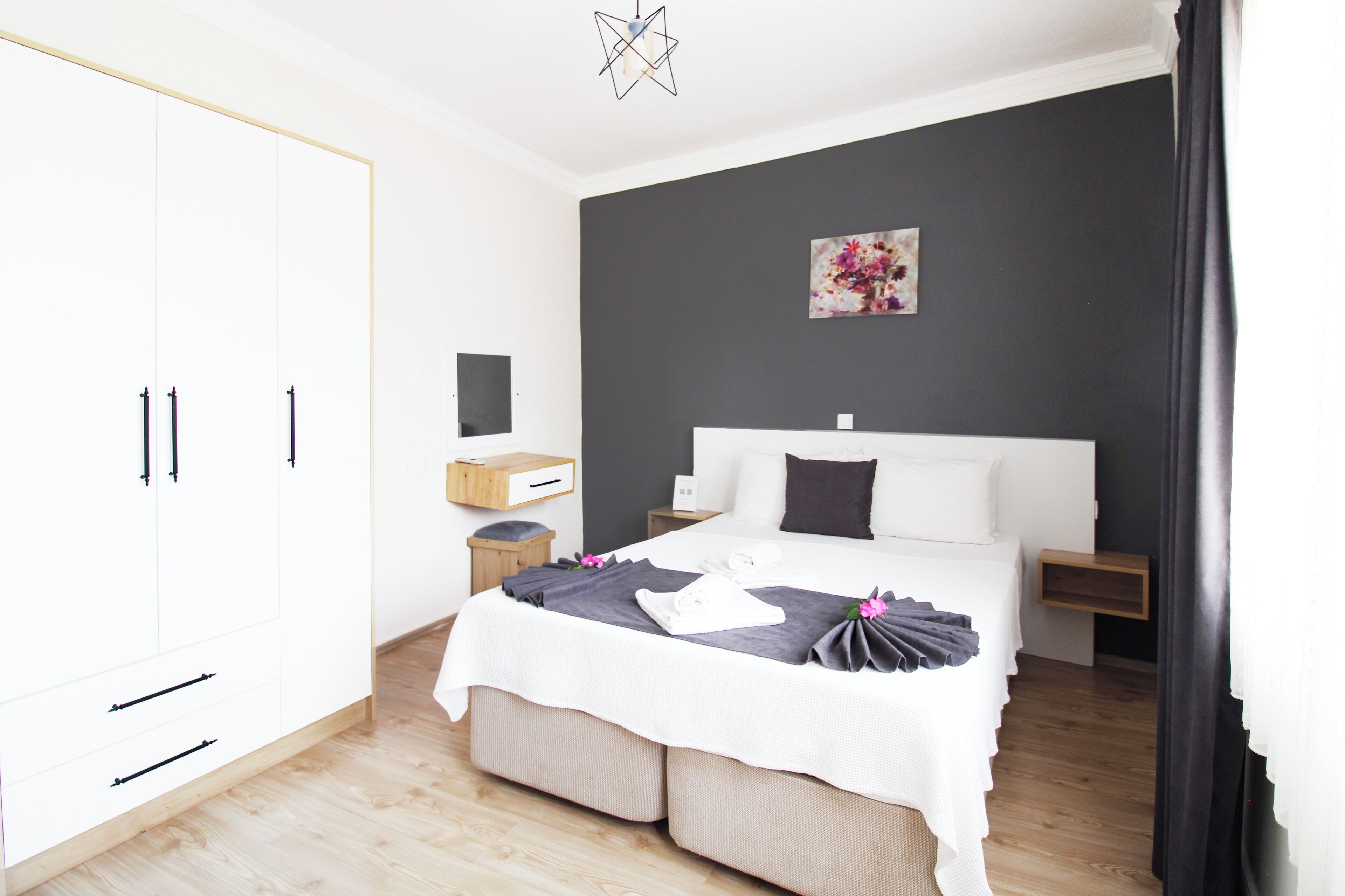 A modern bedroom with a large bed, bedside tables, a wardrobe, and a wall-mounted artwork.