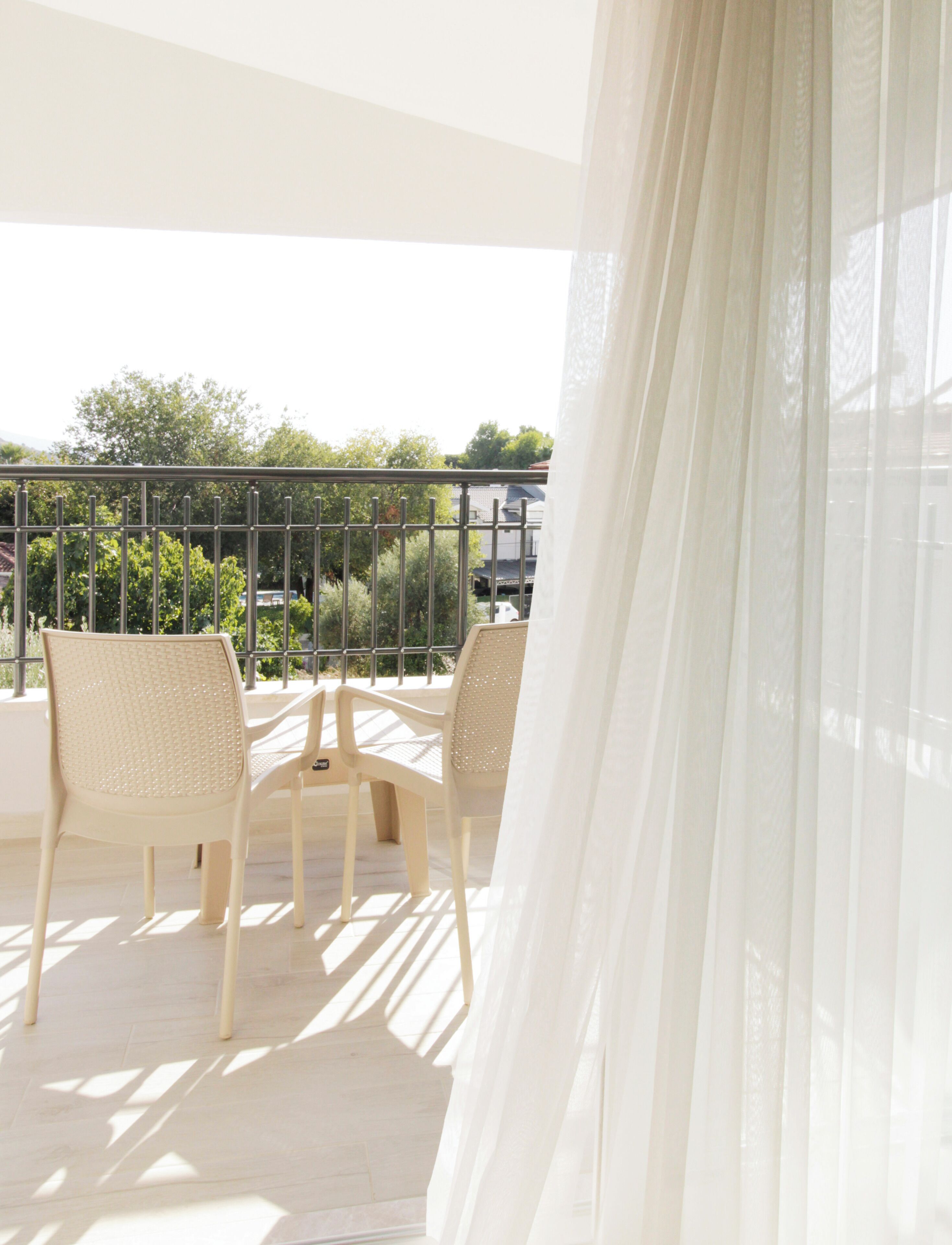Un balcon avec deux fauteuils en osier, une table et une rambarde en métal.