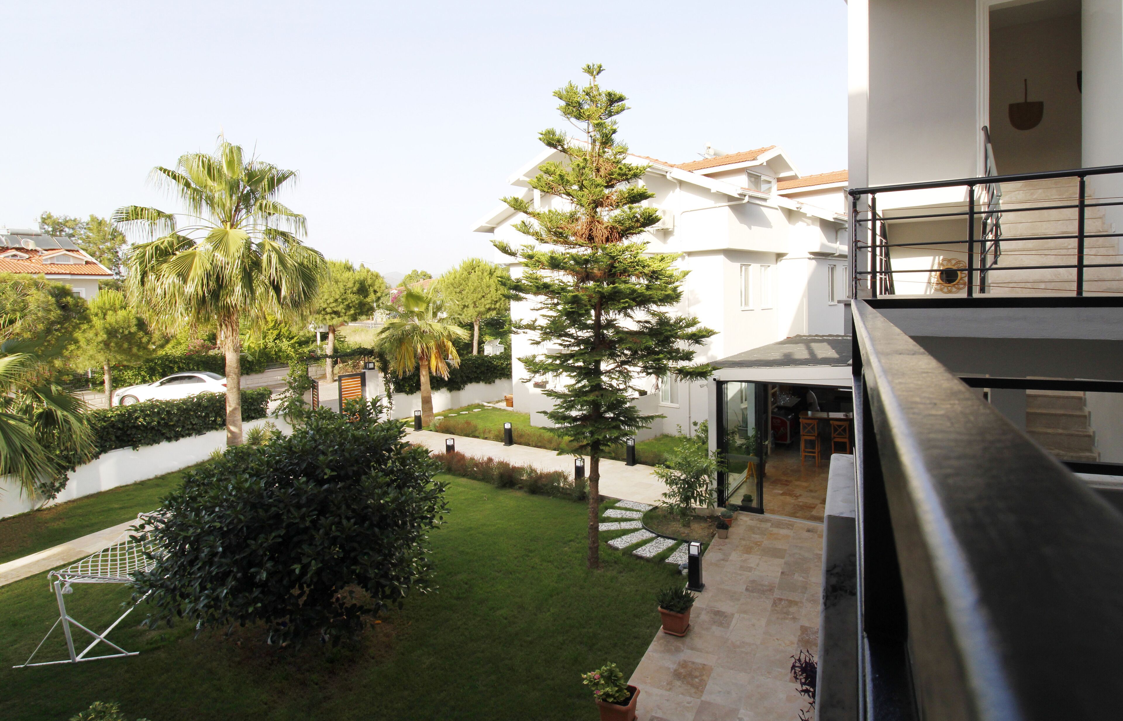 A residential building with a well-maintained garden, a balcony with a metal railing, and a clear view of the surrounding neighborhood.