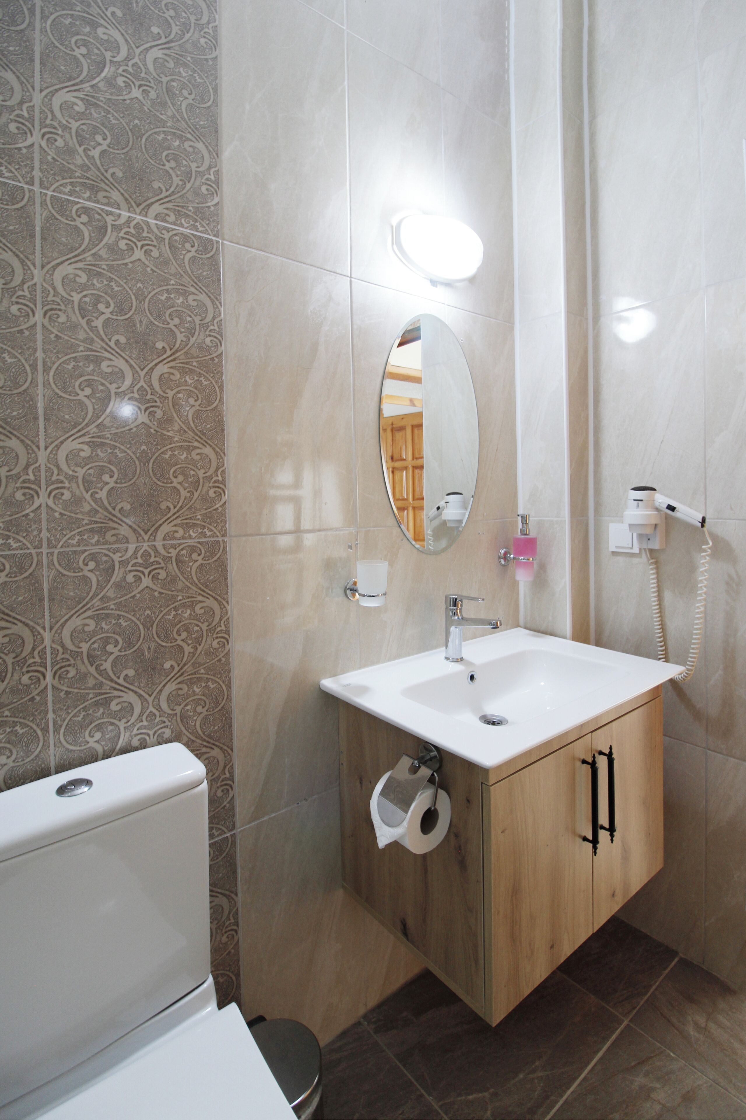 A bathroom with a toilet, sink, mirror, and towel rack.