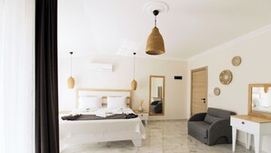 A modern bedroom with a bed, bedside table, and a grey armchair. - Tufan Boutique Hotel & Apart (Ortaca)