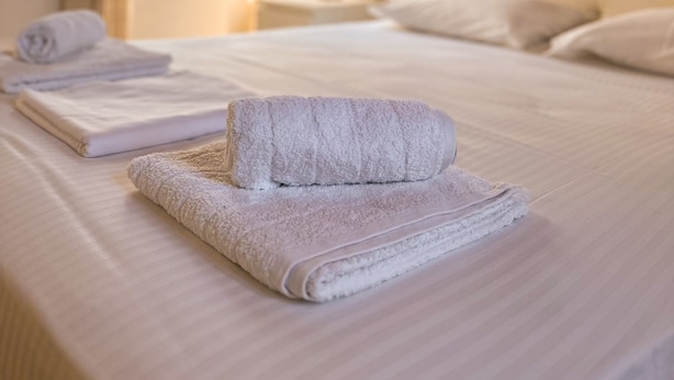 A hotel room with a neatly made bed, a window with curtains, a lamp on a bedside table, and a painting on the wall. - Tinos - House - Sleeps 5 - Pet Friendly - Parking (Tinos)