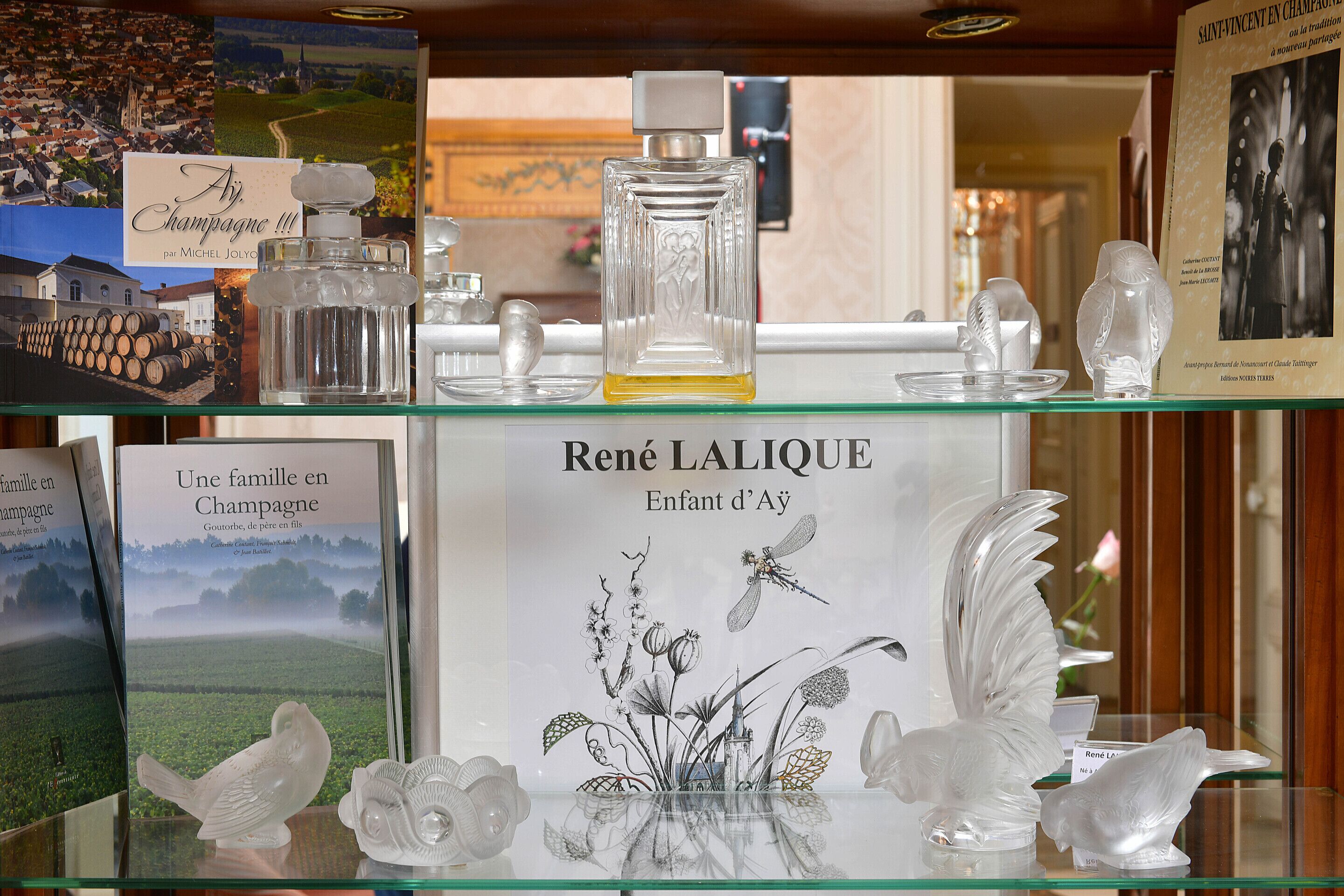 Una exhibición de frascos de perfume y objetos decorativos de René Lalique sobre un estante de vidrio.
