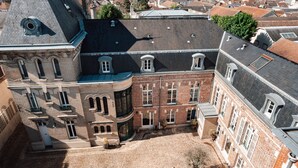 Vista aérea de un edificio histórico con un patio adoquinado, ventanas amplias y una prominente torre en esquina.
