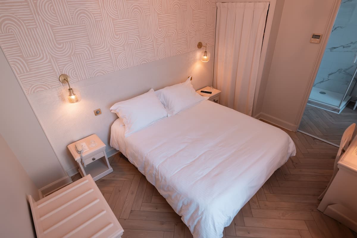 Ein Schlafzimmer mit einem großen Bett, zwei Nachttischen, einem Schminktisch und einer integrierten Dusche.