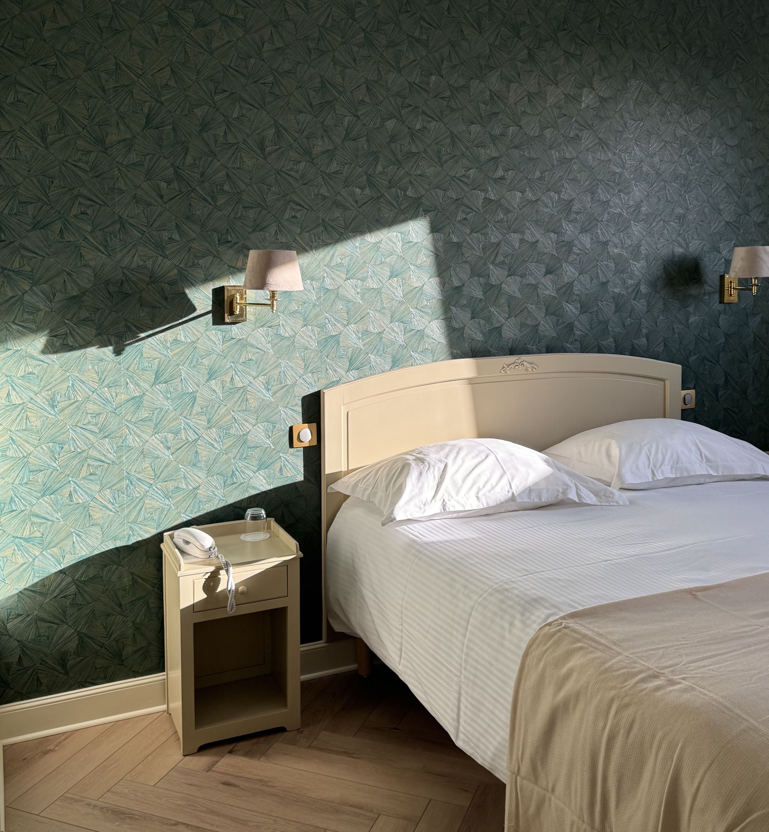 A bedroom with a bed, bedside tables, and wall-mounted lamps.