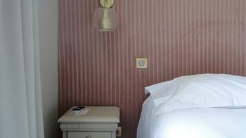 A bedroom with a bed, a nightstand, a lamp, and a wall-mounted light fixture.