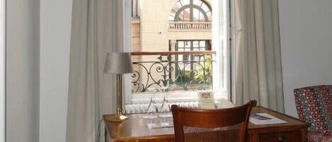 Una habitación con un escritorio de madera, una silla y un ventanal con cortinas.