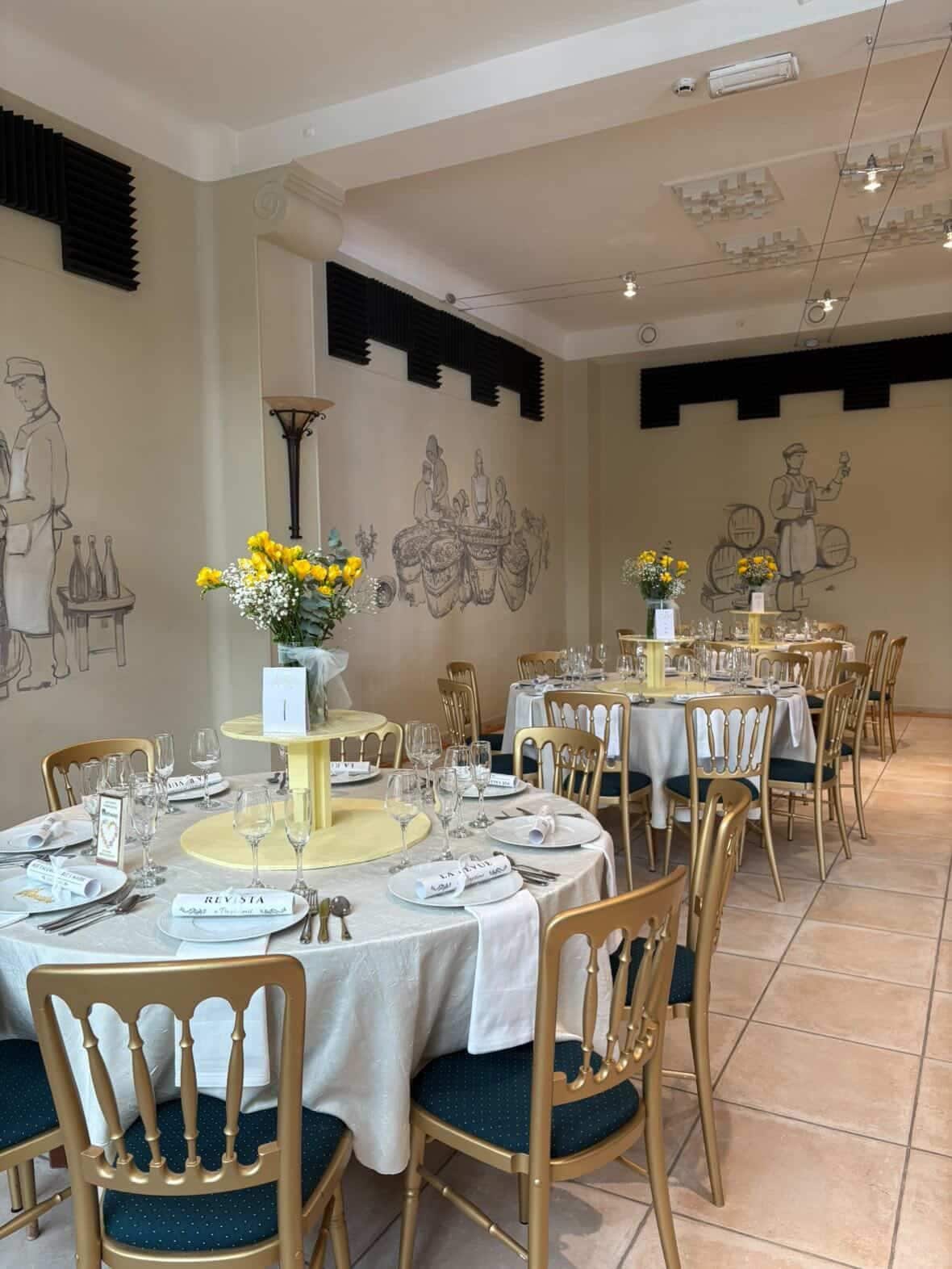 A dining area with round tables, chairs, and a mural on the wall.