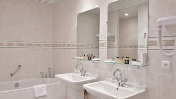 Un baño moderno con dos lavamanos, una bañera y un espejo grande.