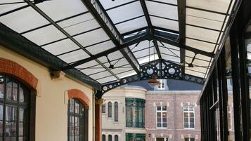 A covered outdoor area with wicker furniture and a brick building in the background.