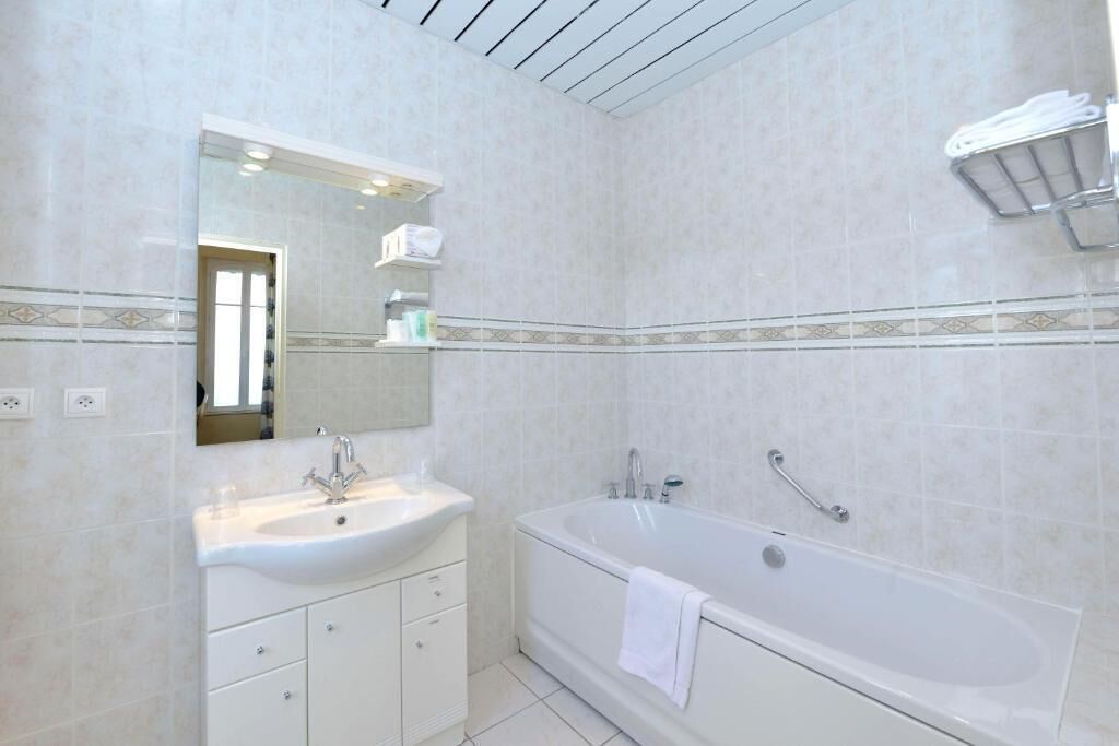 A modern bathroom with a large bathtub, a sink, and a mirror.