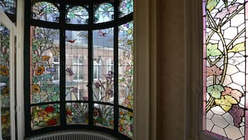 Habitación de esquina con ventanal saliente que presenta vidrieras con motivos florales y de pájaros.