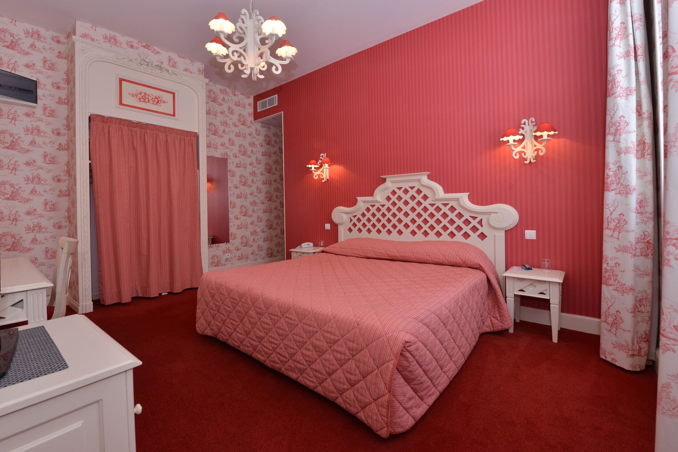 A bedroom with a large bed, a nightstand, a dresser, and a chandelier.