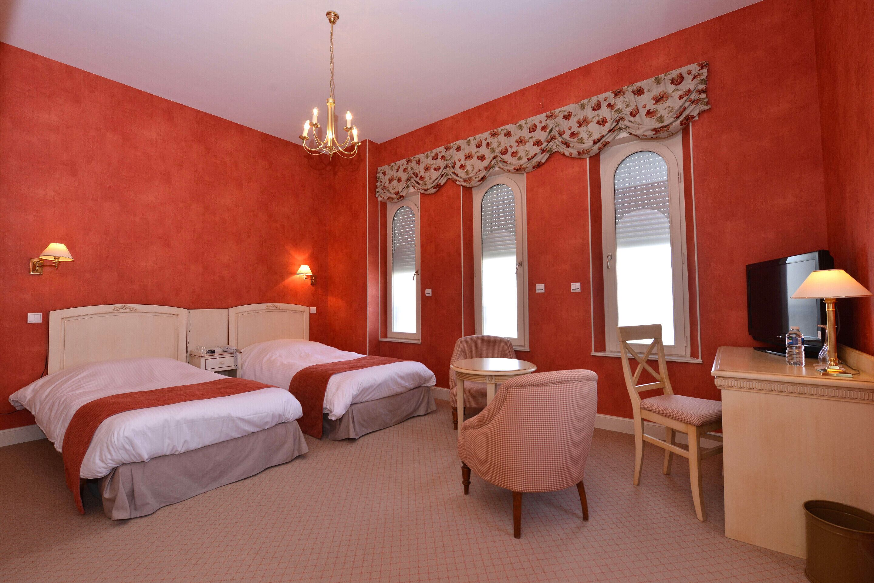 Habitación de hotel con dos camas, un escritorio, una silla, un televisor y un candelabro.