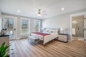 Ein Schlafzimmer mit Bett, Nachttischen, einer Bank und einem Deckenventilator.