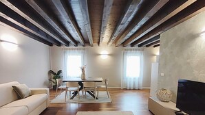 En moderne stue med sofa, fjernsyn, spisebord og stole.