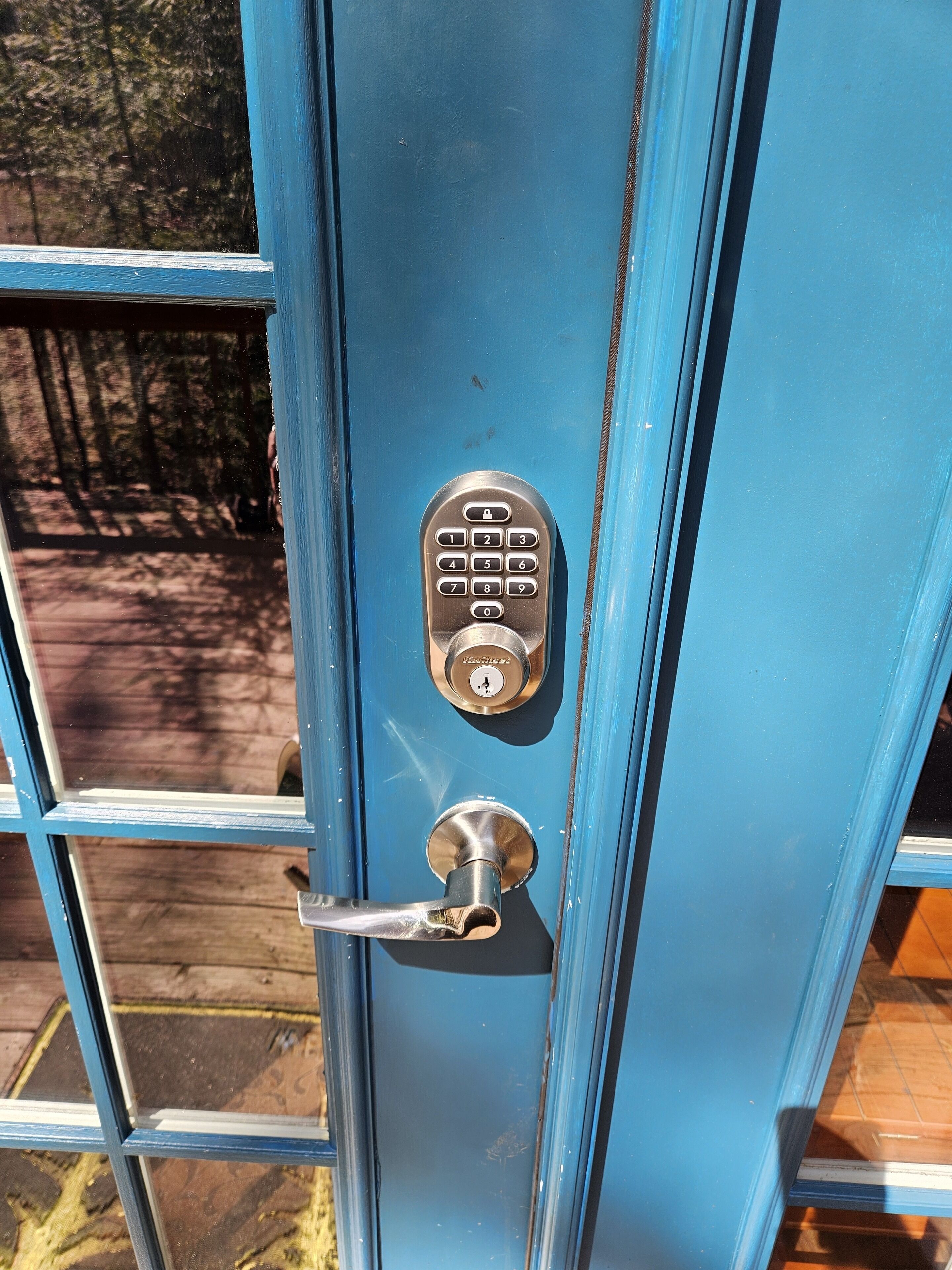 Una puerta azul con un ojo de cerradura y un teclado electrónico.