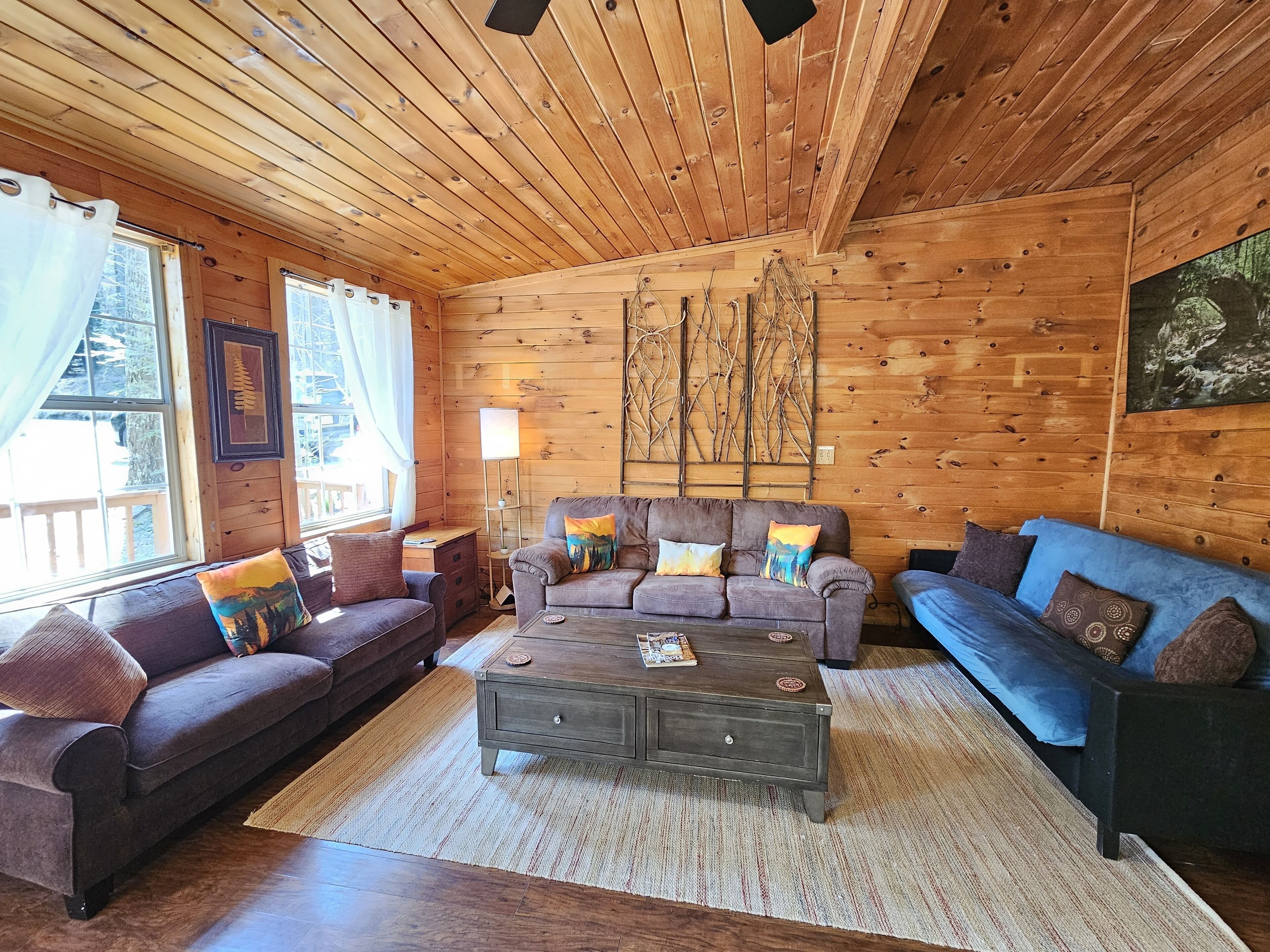 A cozy log cabin interior with a sofa set, a coffee table, and a lamp.