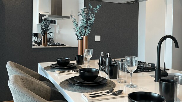 A modern kitchen with a long island, black and white decor, and a large mirror.