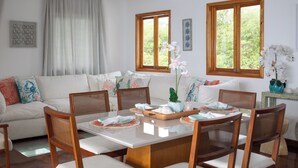 Un comedor con una mesa blanca, sillas de madera y un centro de mesa floral.