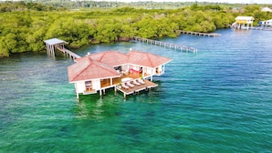 Una casa flotante con techo rojo, varias cubiertas y una zona de estar al aire libre techada.