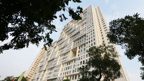 A high-rise building with multiple floors, surrounded by trees and a small pavilion. - Nusantara Rooms By Reccoma (Bekasi)