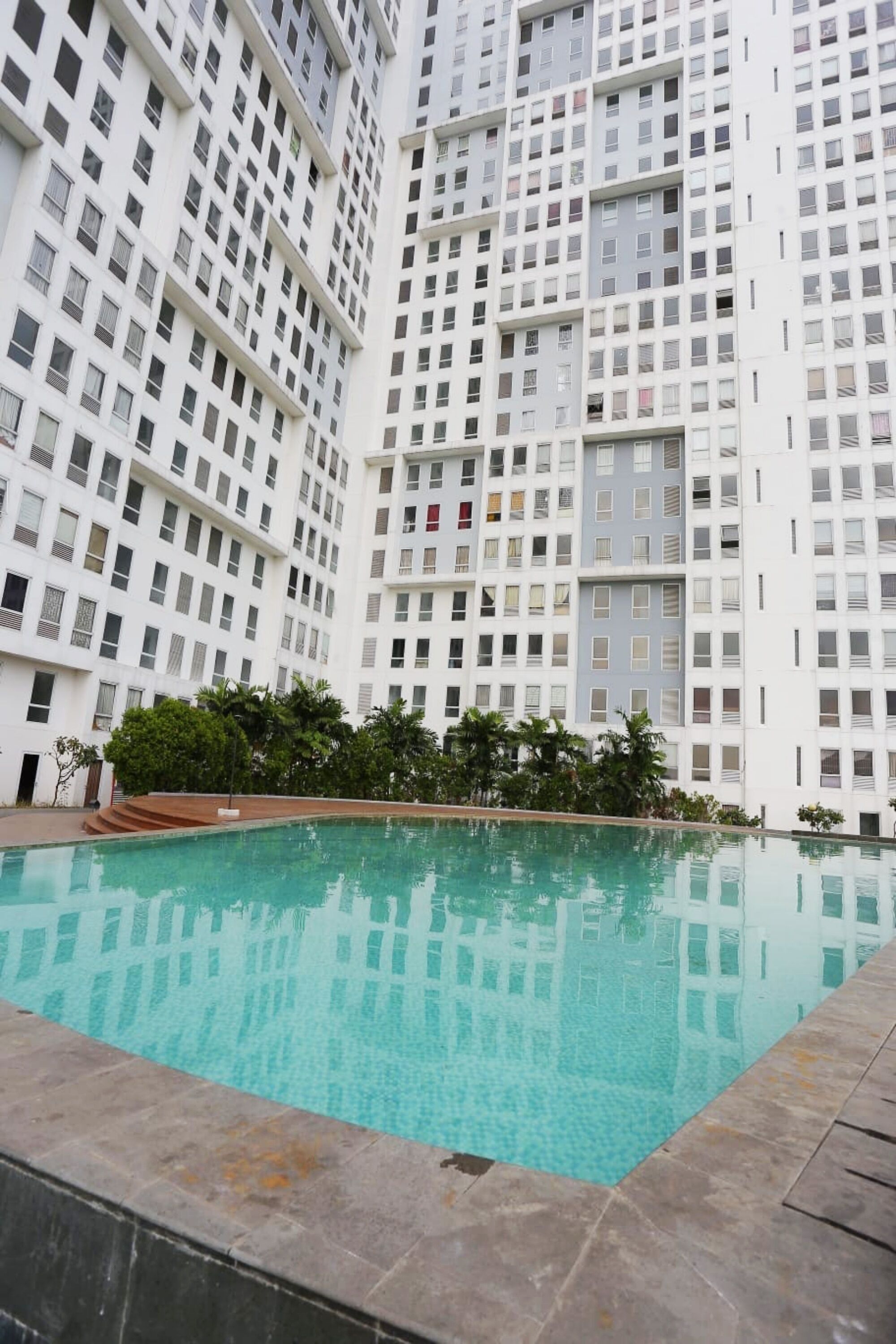 A high-rise residential building with a swimming pool in the foreground.