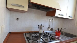 Een keuken met een gasfornuis, een koffiezetapparaat en een rode keukengerei houder.