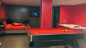 A modern room with a pool table, a red sofa, and a TV mounted on the wall. - Loft 55 m2 Jacuzzi Billard Terrasse 15 min Hyper Centre Strasbourg (Hœnheim)