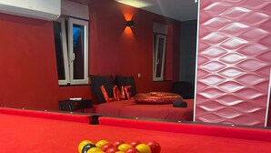 A red pool table with balls arranged in a triangle, a pool cue, and a bed with red bedding and pillows in the background. - Loft 55 m2 Jacuzzi Billard Terrasse 15 min Hyper Centre Strasbourg (Hœnheim)