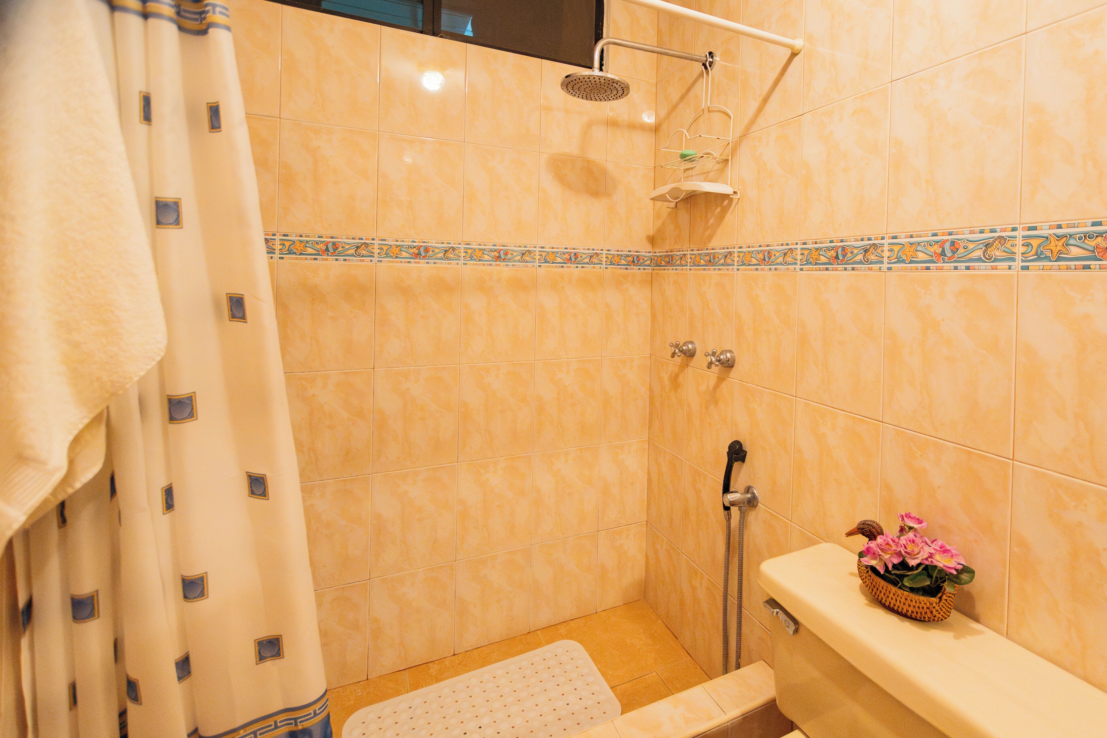 A bathroom with a shower, toilet, and a decorative tile border.
