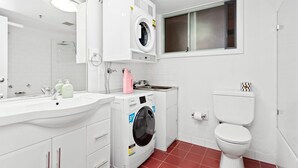 Ein modernes Badezimmer mit Waschmaschine, Toilette und Waschbecken mit Spiegel darüber.