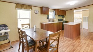 Une cuisine compacte dotée de meubles en bois, d’un îlot central et d’un coin repas avec une table et des chaises.