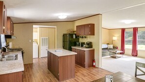 Une cuisine compacte avec des meubles en bois, un îlot central, un réfrigérateur, un four à micro-ondes et un évier.