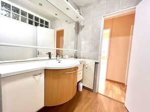 Ein Badezimmer mit Waschbecken, Holzkosmetikschrank, Spiegel und Handtuchhalter.