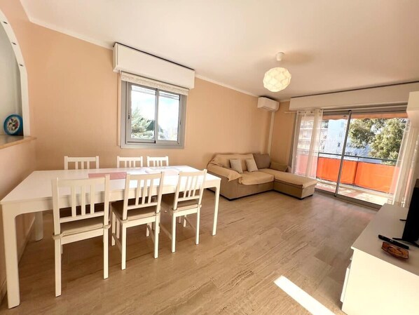 Ein modernes Wohnzimmer mit Esstisch und Stühlen, einer Couch und einem großen Fenster mit Blick.