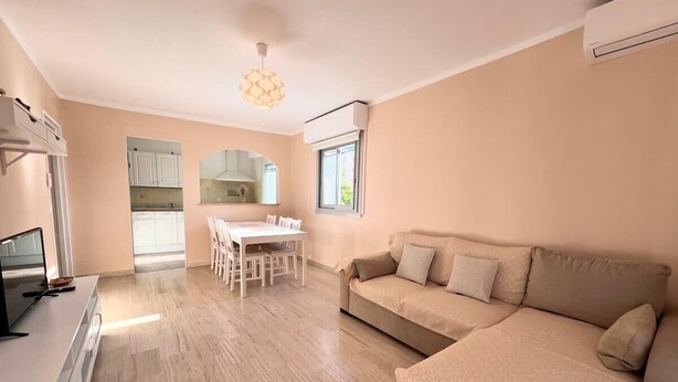 A modern living room with a beige sofa, a dining table, and a TV. - Antibes - 4 people - Parking (Antibes)
