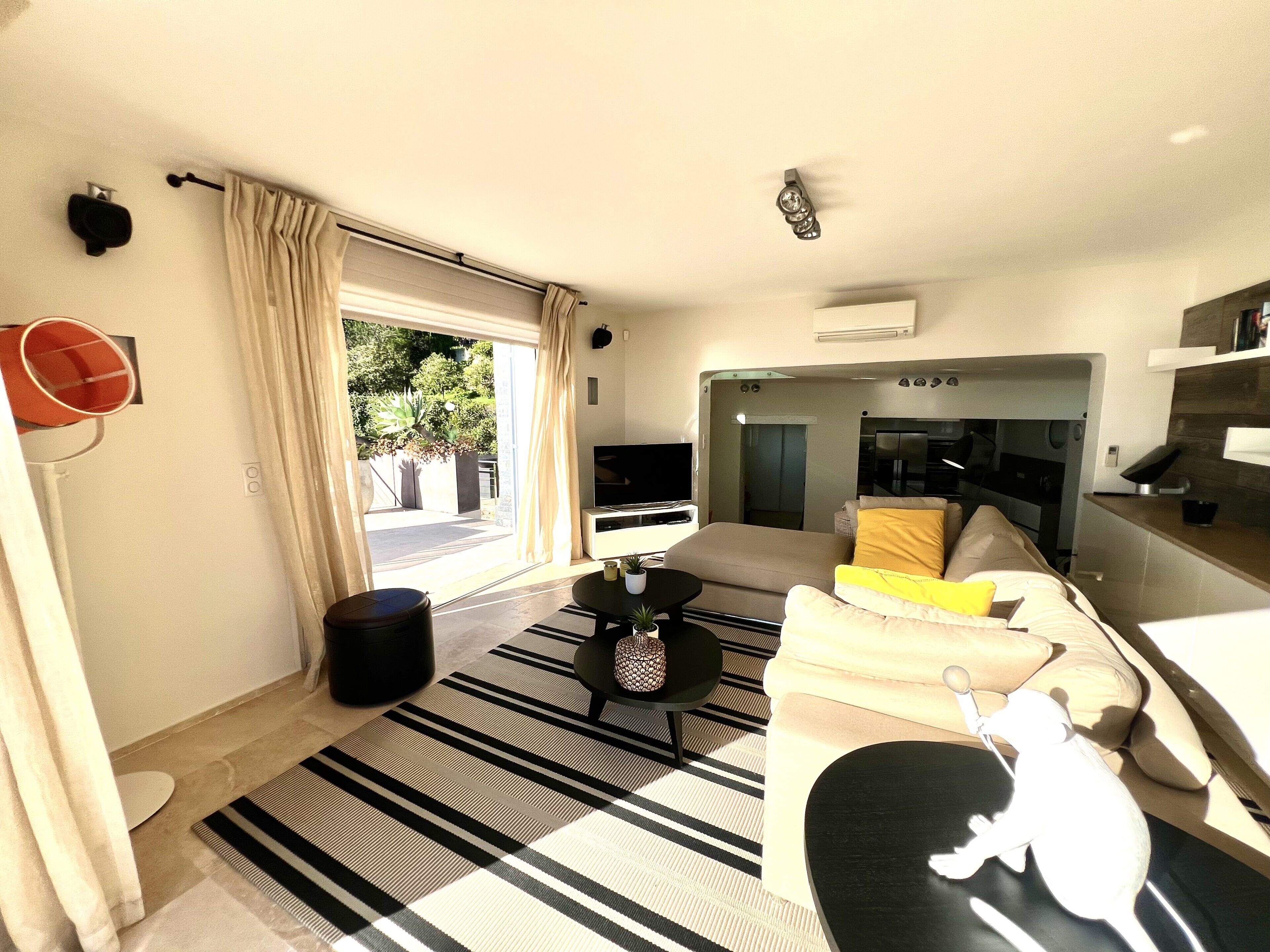 A modern living room with a sofa, coffee table, and a dining area.