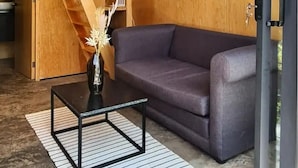 A modern interior with a wooden wall, a purple sofa, a glass door, and a staircase. - Cabañas Grasshopper SHIELD (Tepoztlán)