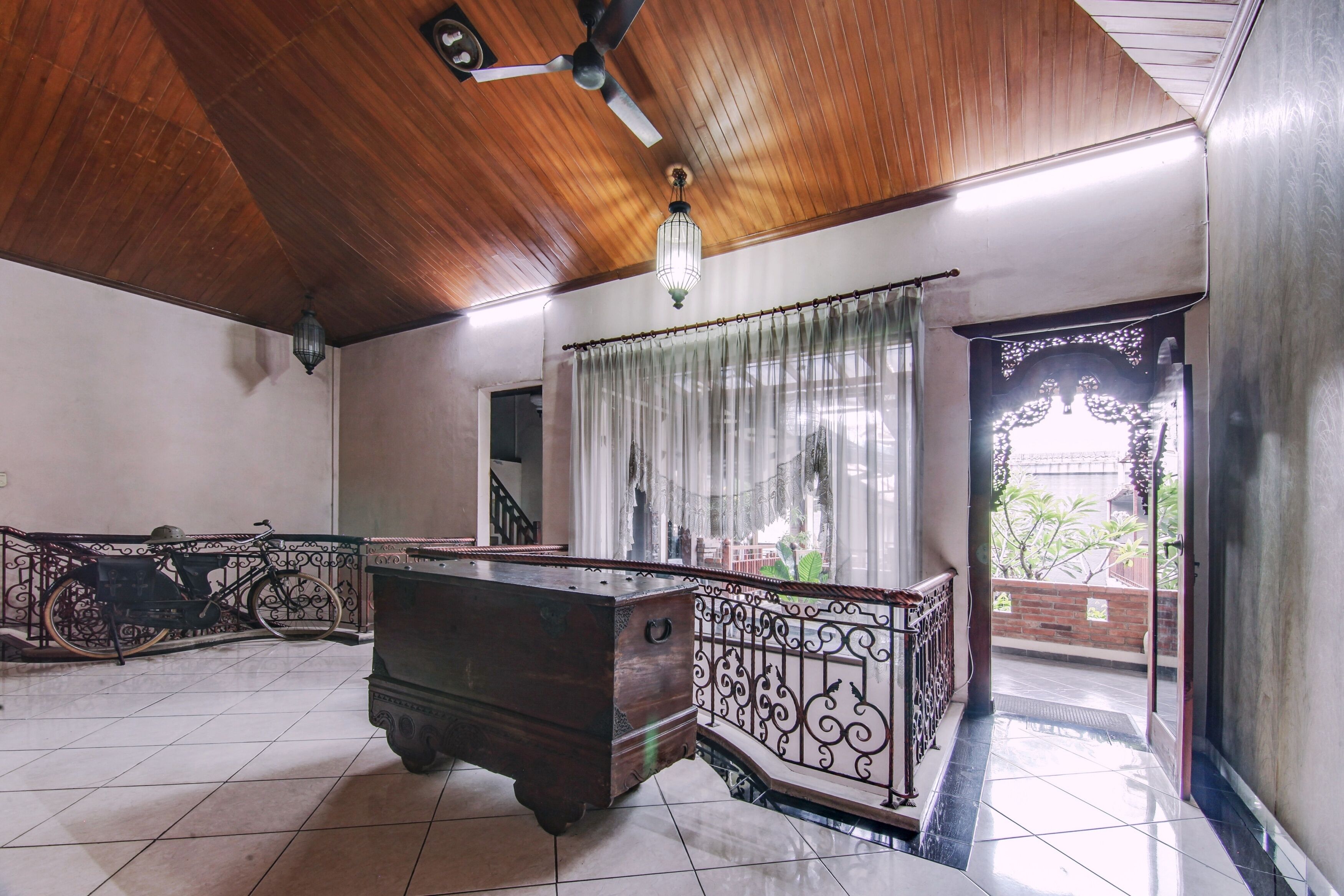 A spacious room with a wooden ceiling, a large desk, and a balcony with a view.