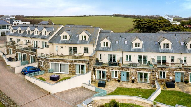 A row of modern, two-story houses with sloped roofs, large windows, and a well-maintained lawn. - Beachside luxury apartment with sea view balcony and parking (Padstow)