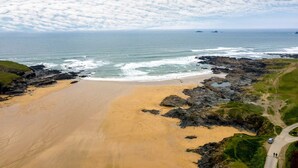 A coastal landscape with a sandy beach, rocky outcrops, and a clear sky. - Beachside luxury apartment with sea view balcony and parking (Padstow)