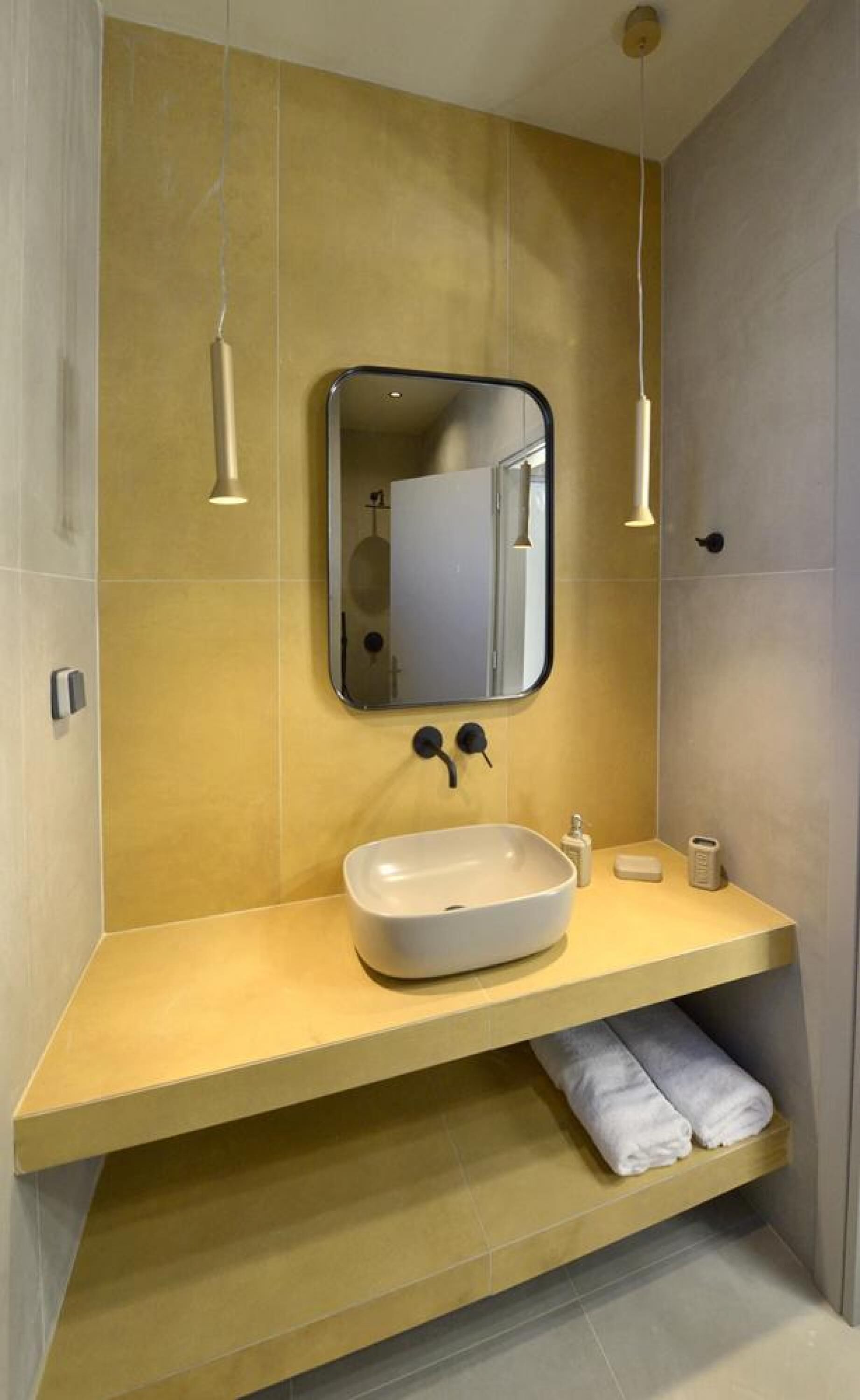 A modern bathroom with a beige vanity, a large mirror, and two pendant lights.