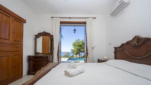 A bedroom with a large bed, wooden wardrobe, and a view of a swimming pool. - Villa Ariadne in Argaka (Argaka)