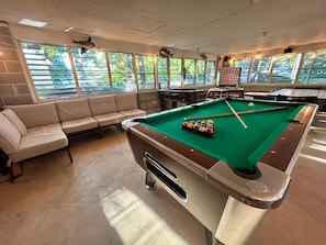 A pool table with balls, a sofa, and a brick wall.