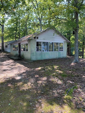 A small, single-story building with a gabled roof, surrounded by trees.